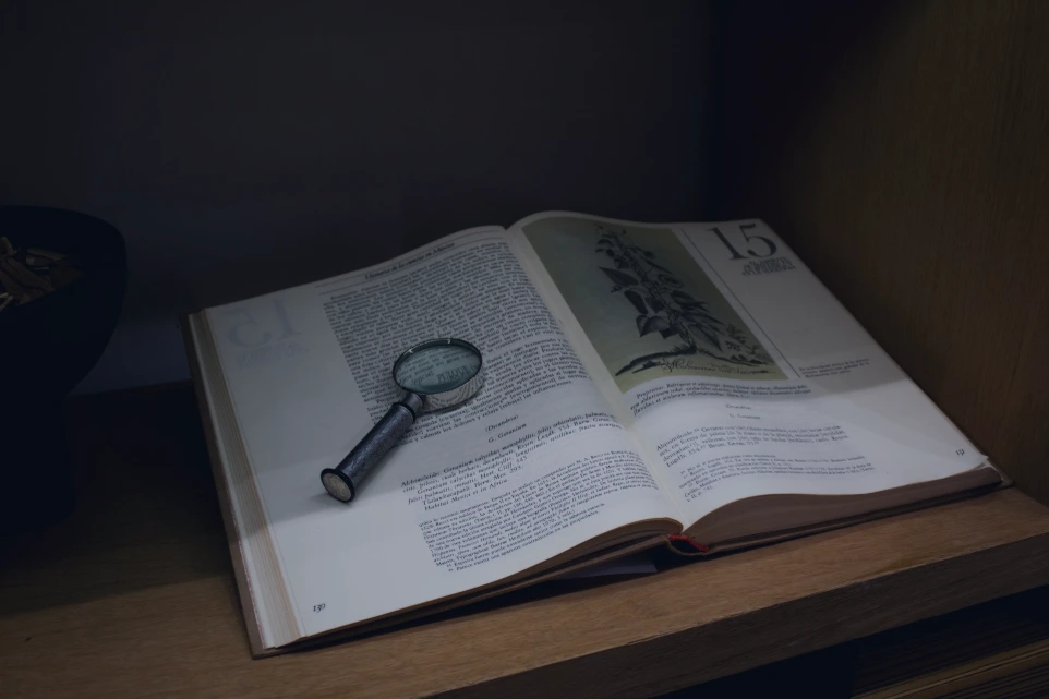 an open book with a magnifying glass on top of it